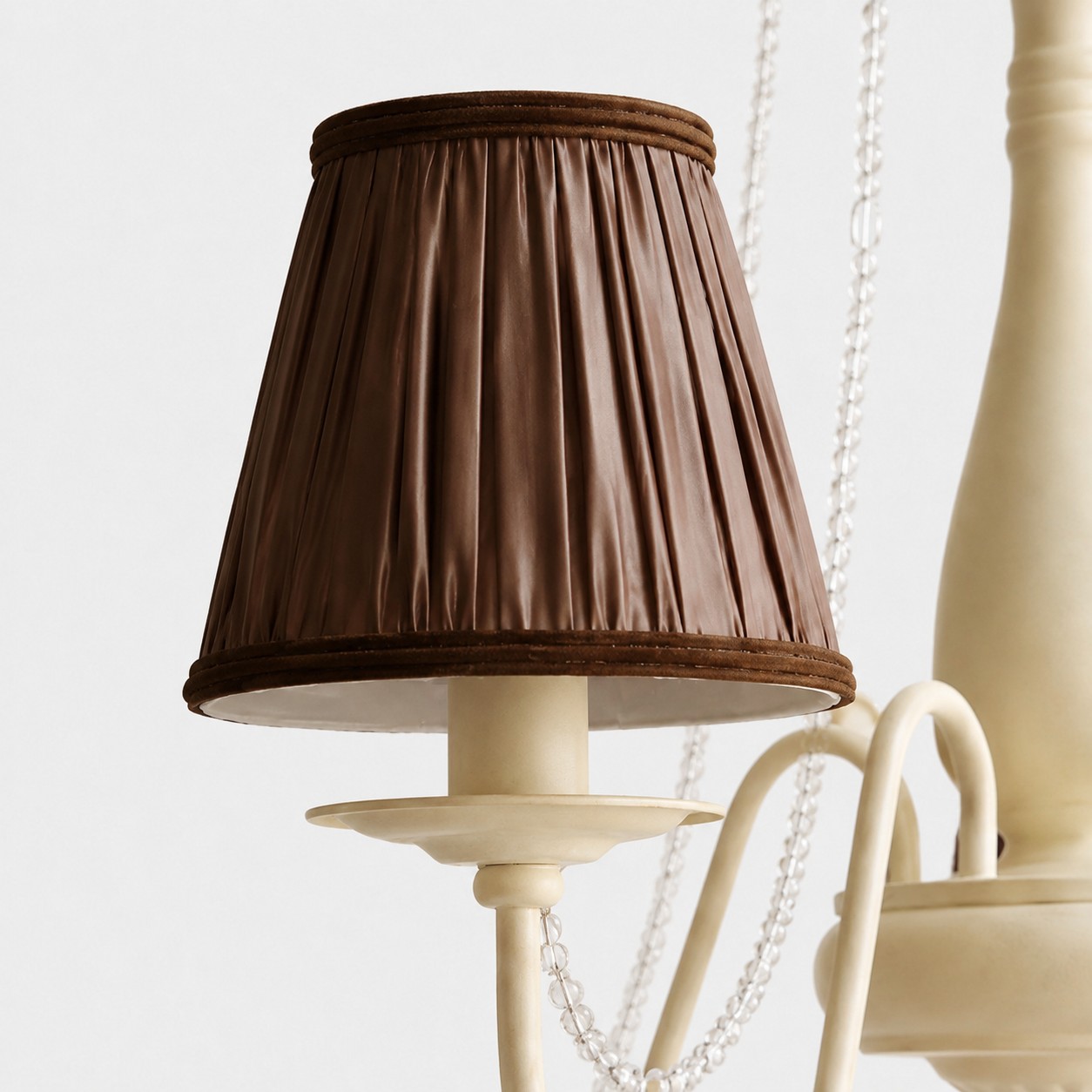 Close-up of pleated brown fabric chandelier shade with wrapped trim